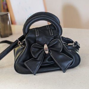 Small black purse/satchel with contrast stitching and a bow; removable strap